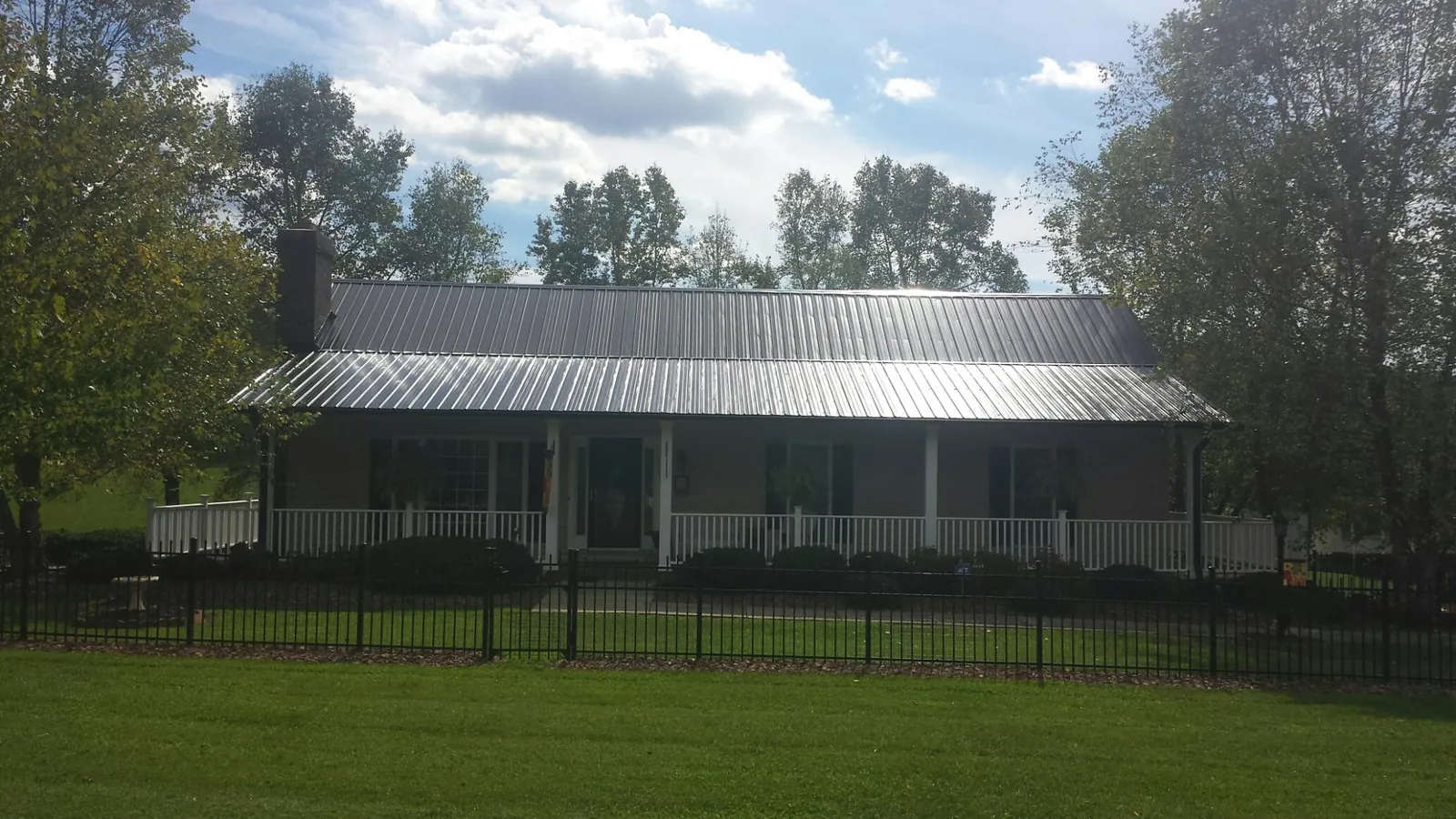 Gray metal roof on a brick ranch with a full width front porch — Gutter Guard Installation work by our crew in Brooksville