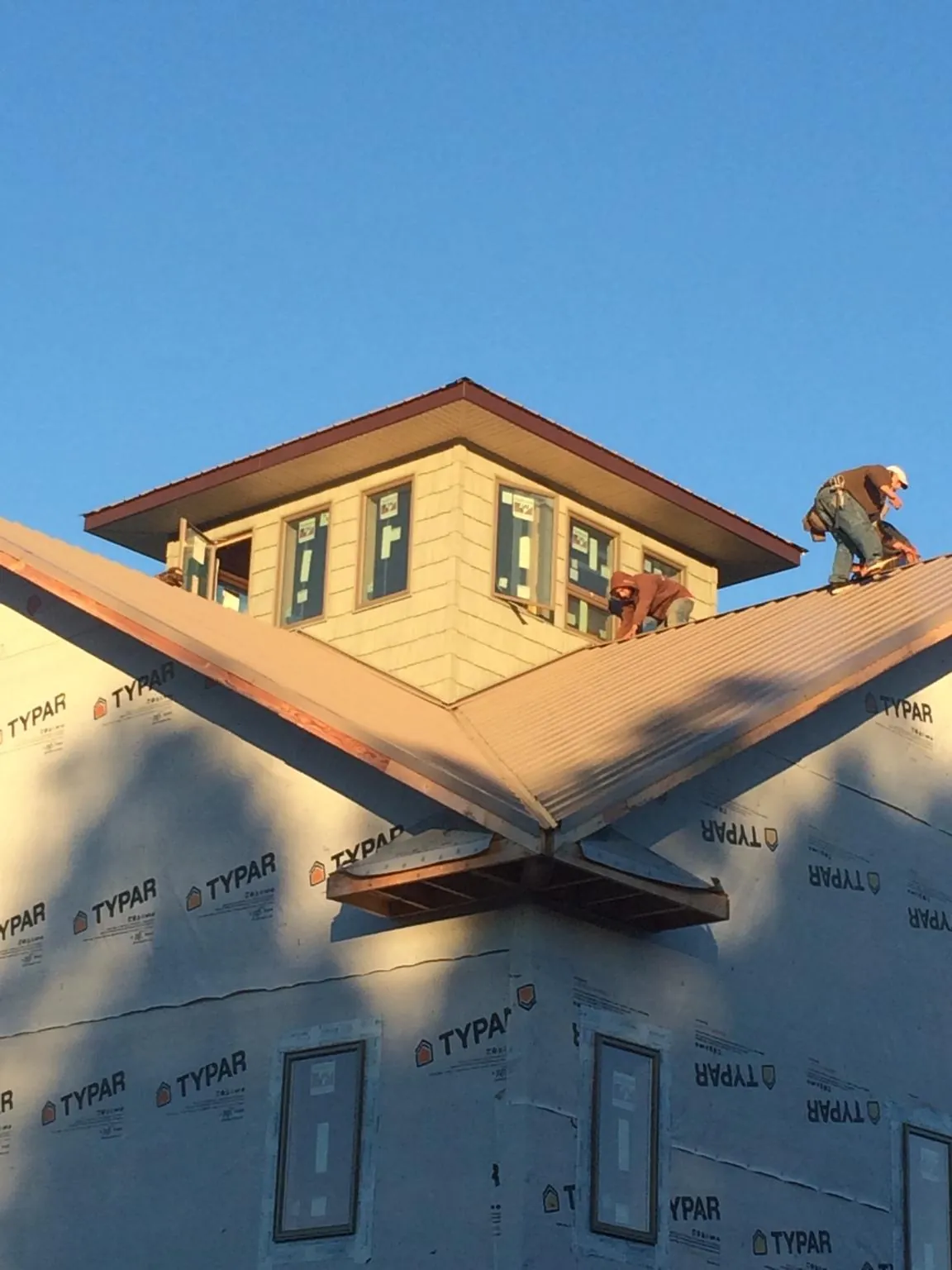 Roofers working around a rooftop cupola on a new metal roof at sunset — Roof Waterproofing in Brooksville by Roofing Brothers